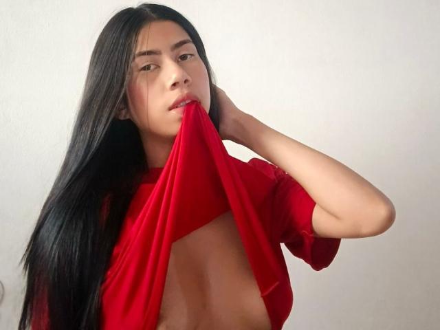 ChloeStone's red shirt, showing her tan skin, is pulled up, revealing her bare, curvy ass and red thong. She's on her knees, with black hair, and a gold anklet.