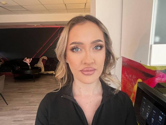 NoraSilk tiene el cabello rubio y ondulado, ojos azules y labios rosados y carnosos. Lleva una camisa negra, y sus senos son pequeños, con una ligera línea bronceada visible..