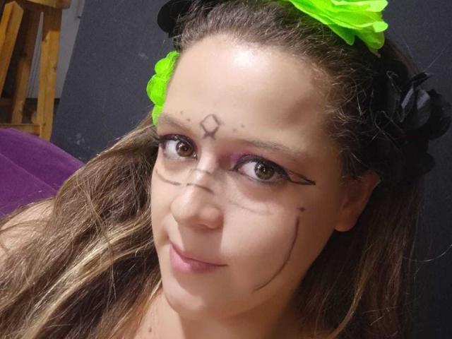 CleareRems ha la pelle marrone chiaro, una fascia verde, capelli neri con un fiore verde neon, e linee di trucco nero marcate sulla fronte e sulle palpebre, con un sorriso appena accennato..