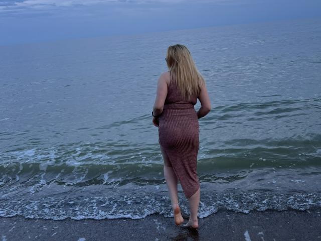 Les fesses de UniqueLady, en string rouge, mettent en valeur son bronzage et ses fesses rondes, à la peau lisse. L'attention est portée sur ses fesses, centrées dans le cadre..