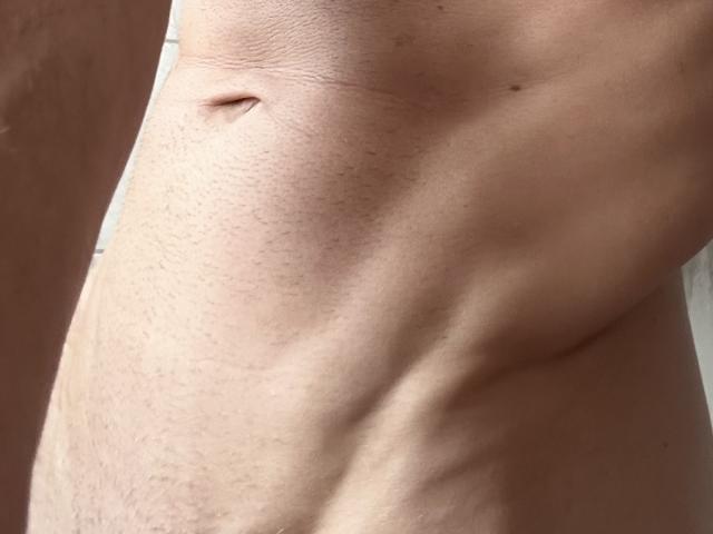 Mamba69's bare, slightly hairy, muscular torso with a small navel and subtle ribcage showing. Light skin with visible texture and slight shadowing.