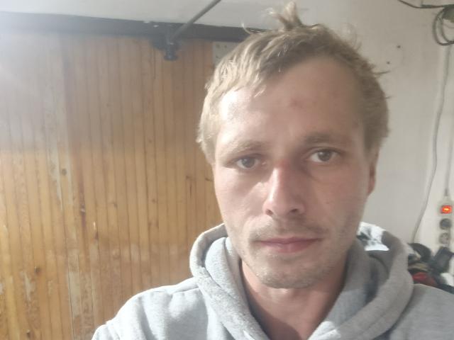 TomTechh has a slightly messy, light brown, tousled haircut, a small bruise on his forehead, and is wearing a grey hoodie, looking straight into the camera.