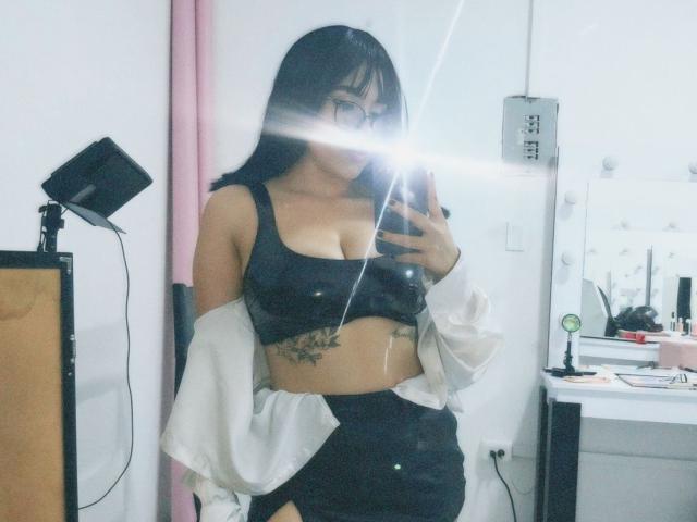 CelesteRusso with medium tits in a black sports bra, black pants, white jacket off-shoulder, black hair, glasses, mirror selfie, camera flash, visible tattoo under sports bra.