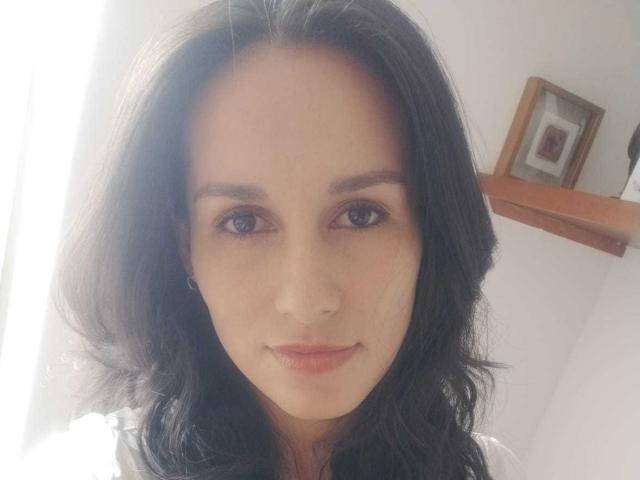VanesaValet tiene el cabello negro de longitud media, ojos azules y una ligera sonrisa. Lleva una camisa blanca, y en el fondo, en un estante de madera, hay una pequeña foto enmarcada..
