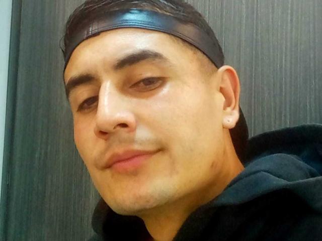 ErickGarciax, short black leather headband, black hoodie, slight smile, ear with tiny stud, short dark hair, light skin, brown eyes, subtle facial stubble, slight blush on cheeks.