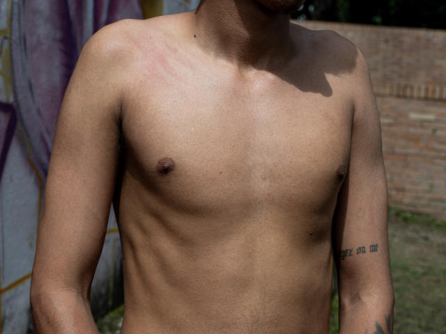 JacobVillalobos's bare chest, showing small brown nipples and a tattoo with numbers on his right arm. His skin is tan with some redness on his upper chest.