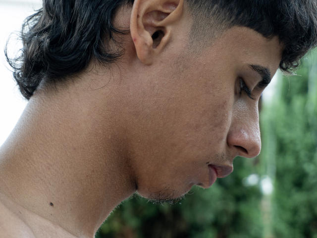 JacobVillalobos has a dark, curly-haired profile, showing his ear, nose, and slightly stubbled chin. His skin is tan with a small mole near his mouth.