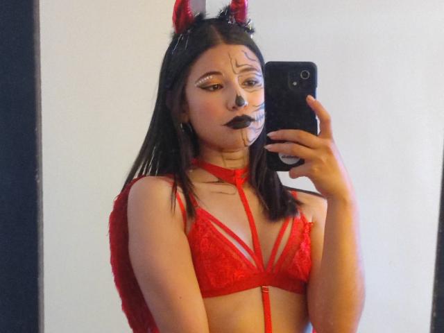 SofiaZen in red lace lingerie with straps, black makeup, and red devil horns, taking a mirror selfie with her phone, showing her tits and red bra.