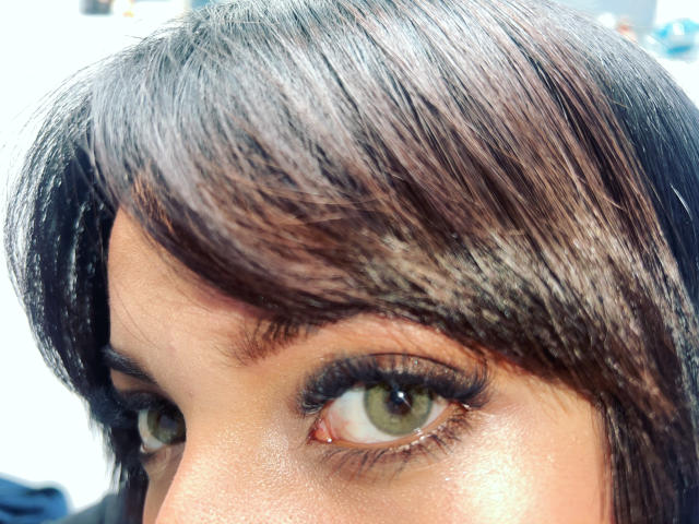 LillyTaylor's brown eyes with long, thick, black lashes, and a slight tan. She has dark brown, shiny hair with subtle highlights, and a small, visible eyebrow.