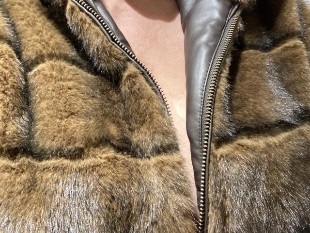 DeesseBleue's chest covered in a brown, puffy, fur-lined jacket with visible black zippers, showcasing the thick, textured fur. The jacket is slightly open, revealing a bit of skin.