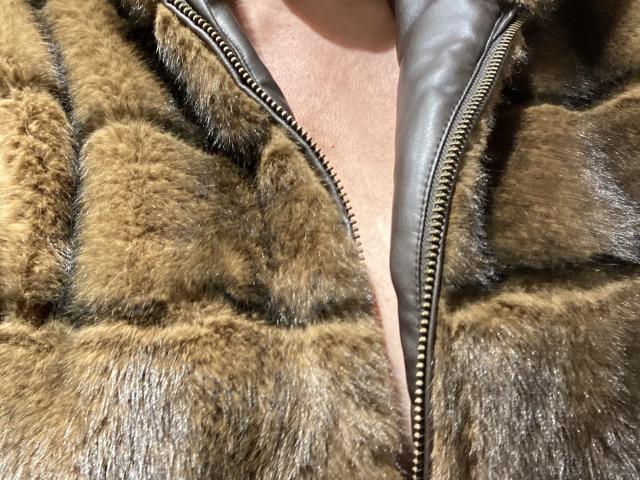 DeesseBleue's ass is covered in a brown, fuzzy, quilted fur jacket with a black leather zipper, showing a bit of pale skin in the middle.