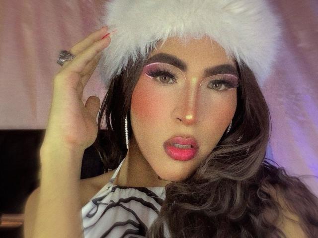 FlorenceLambert with pink makeup, white furry hat, long wavy brown hair, and pink lipstick, holding her hat, showing off her ring and pink nails, with her tits slightly visible.