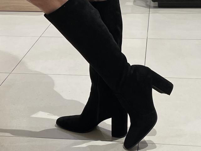 DeesseBleue's black, suede, knee-high, chunk-heel boots with a small, square, block heel are standing on a white-tiled floor, showing a shadow beneath her boots.