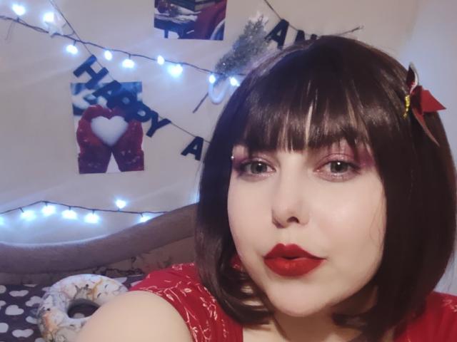 WhitteLotus has pale skin, red lipstick, black bob with red bow, pink eyelids, and a nose ring. Her tits are small, and she's wearing a red shirt.