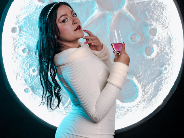 VictoriaRiver with wet black hair, white ribbed dress, pearl headband, holding pink wine glass, finger in mouth, looking seductive, blue light, moon-like circular background.