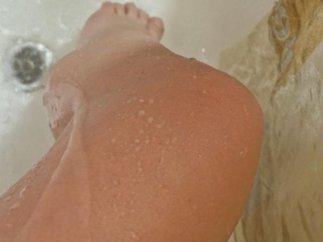 Jumiera's wet ass, with droplets of water, in a shower, showing a close-up of her buttocks, with her foot slightly visible in the background.