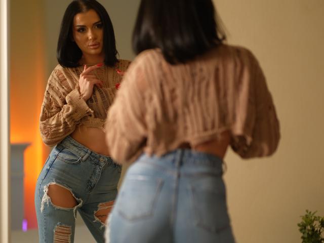 NaughtyyChloe with medium tits, wearing a brown knit crop top and ripped jeans, stands facing another woman with a similar outfit, who is seen from the back.
