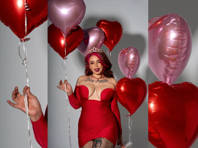 Alexandrapsique with pink and red heart balloons, wearing a red dress, long sleeves, tiara, and fishnet stockings, showing big tits and a tattoo on her thigh.