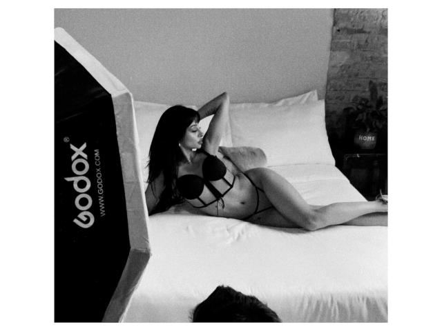 ThaliaCollins is lying on a bed in black lingerie, with her hand behind her head and a seductive look, showing her tits and a slim, sexy body.
