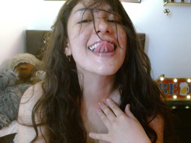 MargaritaDudole, with wet tits and tongue out, has messy brown hair and a hand on her chest, in a slightly blurry, provocative selfie.