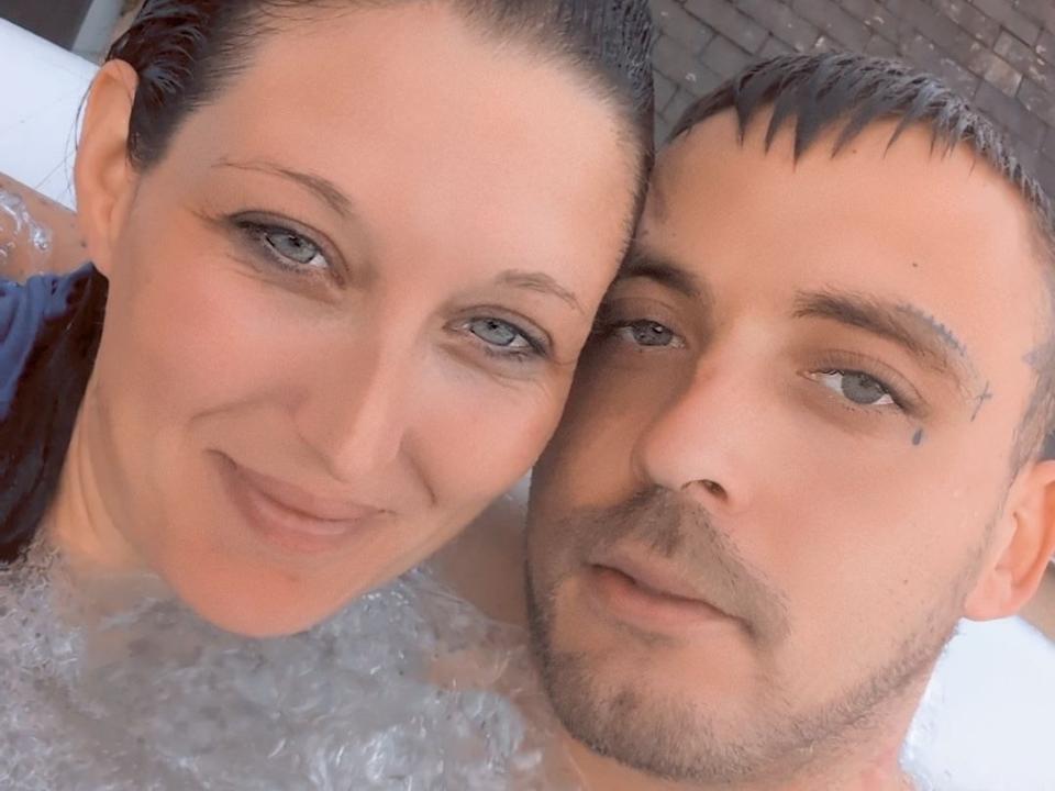 Ticttac with wet, dark brown hair and blue eyes, and Ticttac with short, dark brown hair and grey eyes, both smiling at the camera, in a bubble bath.