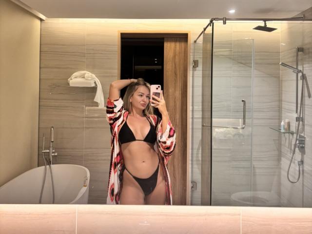 EvaAdderiy in a mirror selfie, wearing a black bikini with high-cut panties, and a red-patterned robe, exposing her tits and pussy, in a modern bathroom.