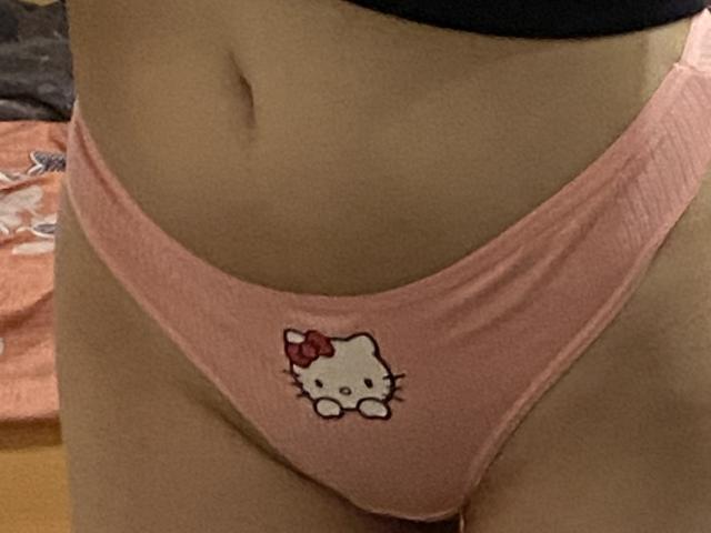 LilyLottie's pink panties with a Hello Kitty logo on the front, showcasing her bare lower belly and a small navel. Her pussy is partially covered by the panties.