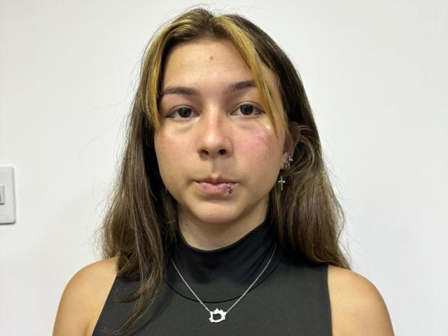 LuxuryLoveers has a cute face, brown eyes, and a small nose piercing. She's wearing a black sleeveless top with a silver necklace and has blonde highlights in her brown hair.