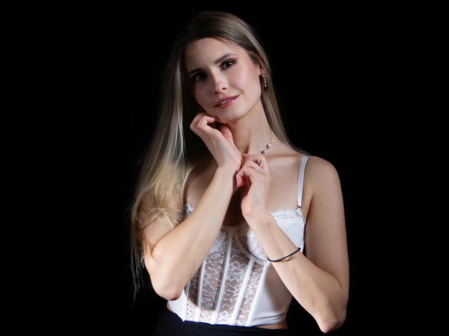 CatrinLips with long blonde hair, wearing a white lace-up corset, hands near chin, black background, subtle smile, small tits, slim, cute, earrings, bracelet, soft lighting.