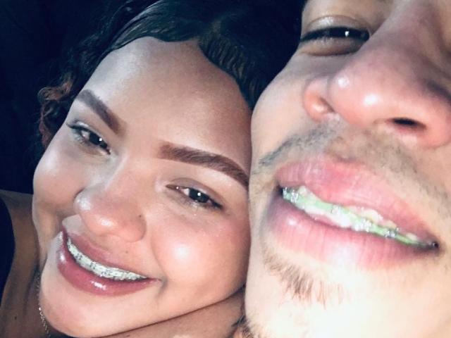 DirtyCoupleXy with shiny tits and white teeth, smiling close to DirtyCoupleXy's pink lips and greenish teeth, both with dark brown hair and light skin.