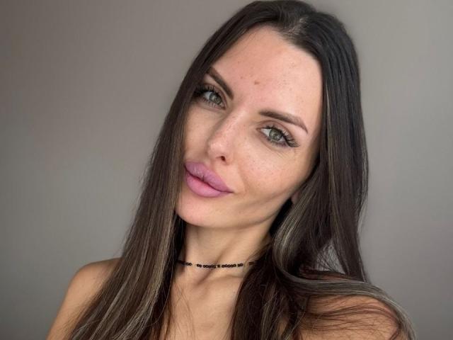 AddisonAdore a de longs cheveux bruns, des yeux bleus et du rouge à lèvres rose. Elle porte un collier noir, et ses seins sont petits avec des taches de rousseur visibles sur sa peau claire..
