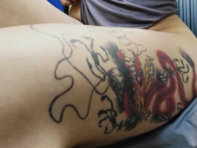 LolyYunno's thigh has a colorful tattoo of a red dragon with black and yellow accents, and black outline puzzle piece design. LolyYunno is wearing a gray shirt.