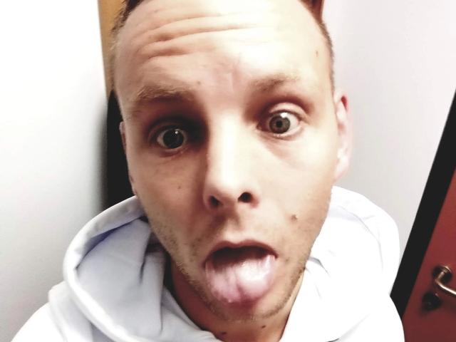 19yayo88-hot a une expression amusante, avec de grands yeux et la langue qui dépasse. Il porte un sweat à capuche blanc, a une calvitie naissante et une petite tache de naissance sur sa joue gauche..