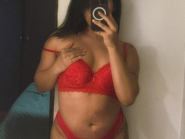 ElizabethMacy wearing red lace lingerie, covering her tits with one hand, holding a phone in the mirror, showing her pussy and a tattoo on her right hand.