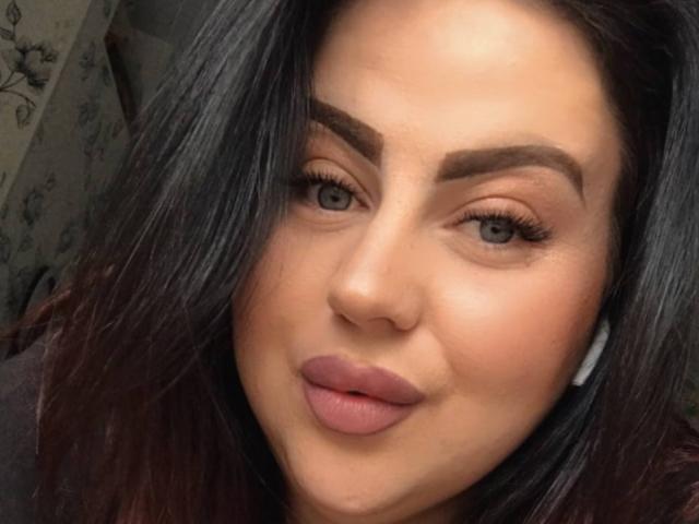 MyraKeldy's face with full, dark eyebrows, long eyelashes, pink lips, and dark, straight hair. She has a light skin tone and wears white earbuds.