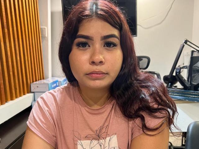 LenaCopers has medium brown skin, long wavy red-brown hair, thick eyebrows, and is wearing a pink shirt with a leaf design. Her tits are small and she has a pouty face.