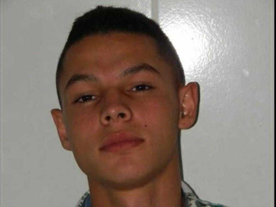 ThomasWill has a short, dark buzzcut, brown eyes, and a slight smile with a small mole on his left cheek. He's wearing a plaid shirt with a blue collar.