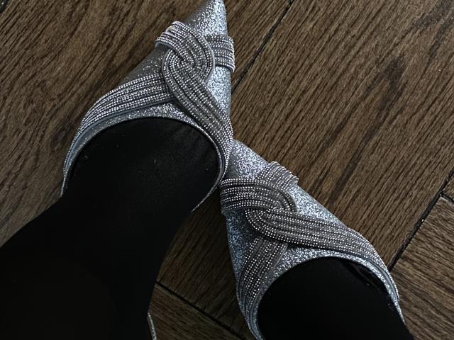 FlyFreedom's feet in sparkly silver high-heels with intricate patterns, black socks, and pointed toes, on a wooden floor. Boobs aren't visible, but the heels are super shiny.