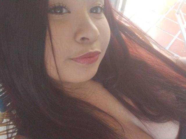 LenaCopers has long, dark brown hair, light skin, and red lipstick. Her small, perky tits are partially visible. She's smiling softly with subtle makeup.