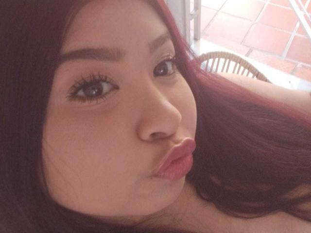 LenaCopers with pouty pink lips, brown eyes, and long dark red hair, making a puckering face, showing off her soft, cute, and slightly chubby face.