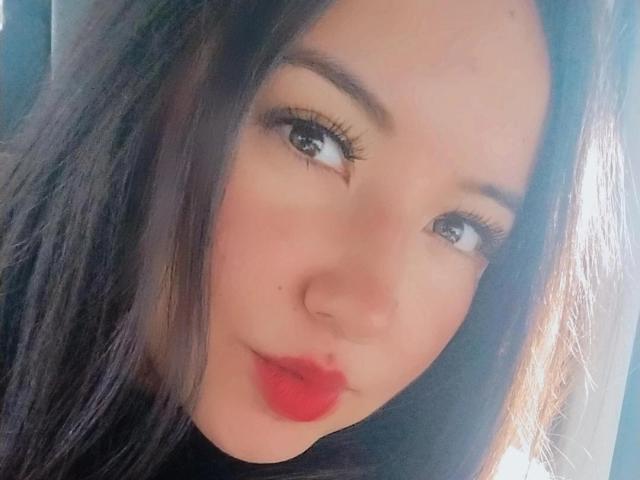 SusanMonroy's face with long black hair, red lipstick, and subtle makeup, showing her pouty lips and cute brown eyes in a soft, natural light selfie.