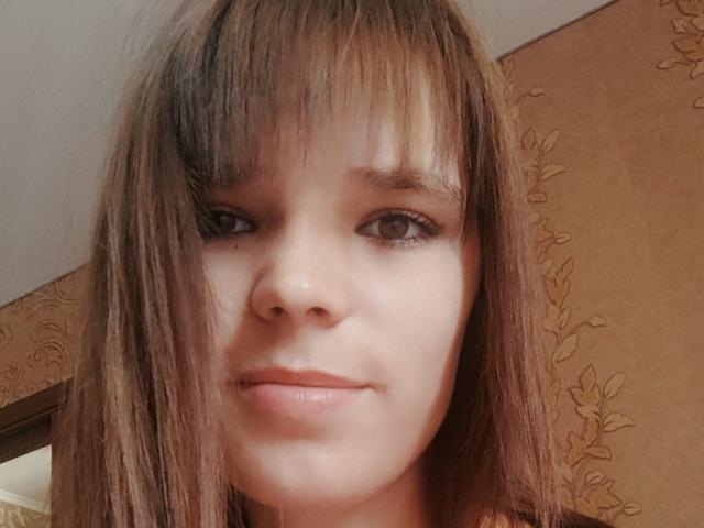 BetteHetty has straight brown hair with bangs, brown eyes, and a slight smile. Her face is centered, showing a smooth, fair-skinned complexion. She's wearing a subtle pink lipstick.
