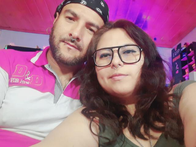 SektethLilith with a bearded guy wearing a black bandana and pink/white polo, and SektethLilith with glasses, wavy brown hair, and a green top. SektethLilith's nose ring is visible.