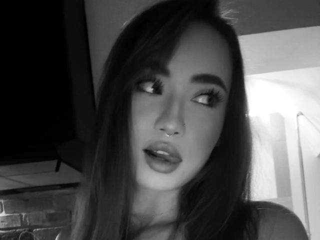 Black-and-white selfie of LexiHerzig-hot with long dark hair, nose ring, and full lips looking to the side. She has thick eyelashes and is slightly open-mouthed.