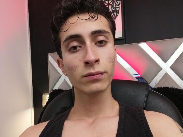 IthanSkin tiene el cabello corto, rizado y negro, ojos marrones y un pequeño piercing en el labio. Lleva una camiseta negra, mostrando un rostro pálido con cicatrices de acné..