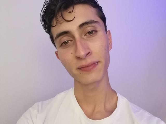 IthanSkin tiene el pelo corto, rizado y negro, un piercing en la nariz y otro en el labio. Lleva una camisa blanca, con una ligera luz morada-azul en su lado derecho..