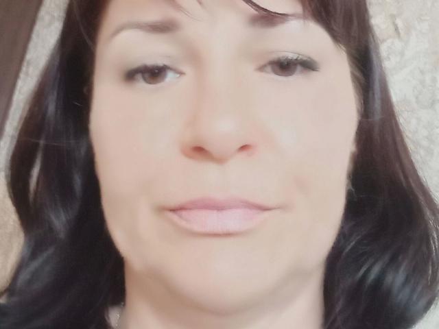 MonicaErotisch-hot has light skin, brown eyes, and dark brown hair. She's smiling slightly with pink lips, and her face is centered in the blurry photo.