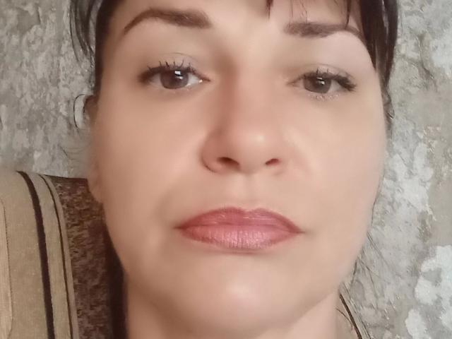 MonicaErotisch-hot's face, showing light skin, brown eyes, black eyebrows, pink lipstick, and short dark hair, with a neutral expression, in a close-up shot.