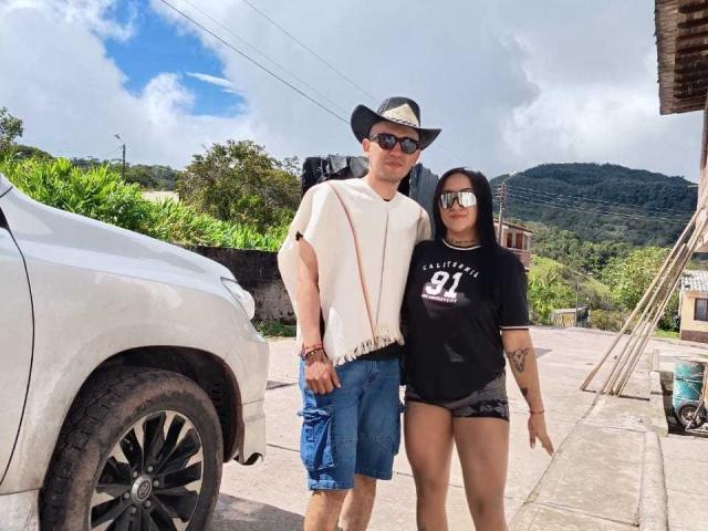 TemptationDual, un ragazzo con un cappello bianco e occhiali da sole, che indossa una camicia bianca e pantaloncini blu, è in piedi accanto a TemptationDual, una ragazza con una maglietta nera e pantaloncini di jeans..