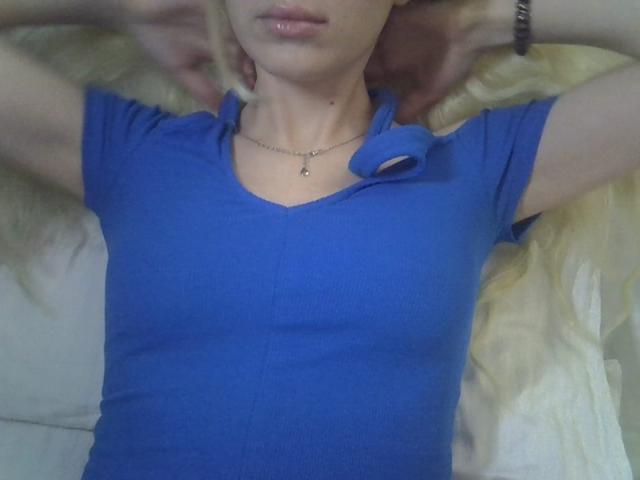 DitaVira's blue ribbed shirt, small tits, slightly visible nipples, arms raised, blonde hair, lips, necklace, bracelet, lying down, soft light, casual, relaxed.